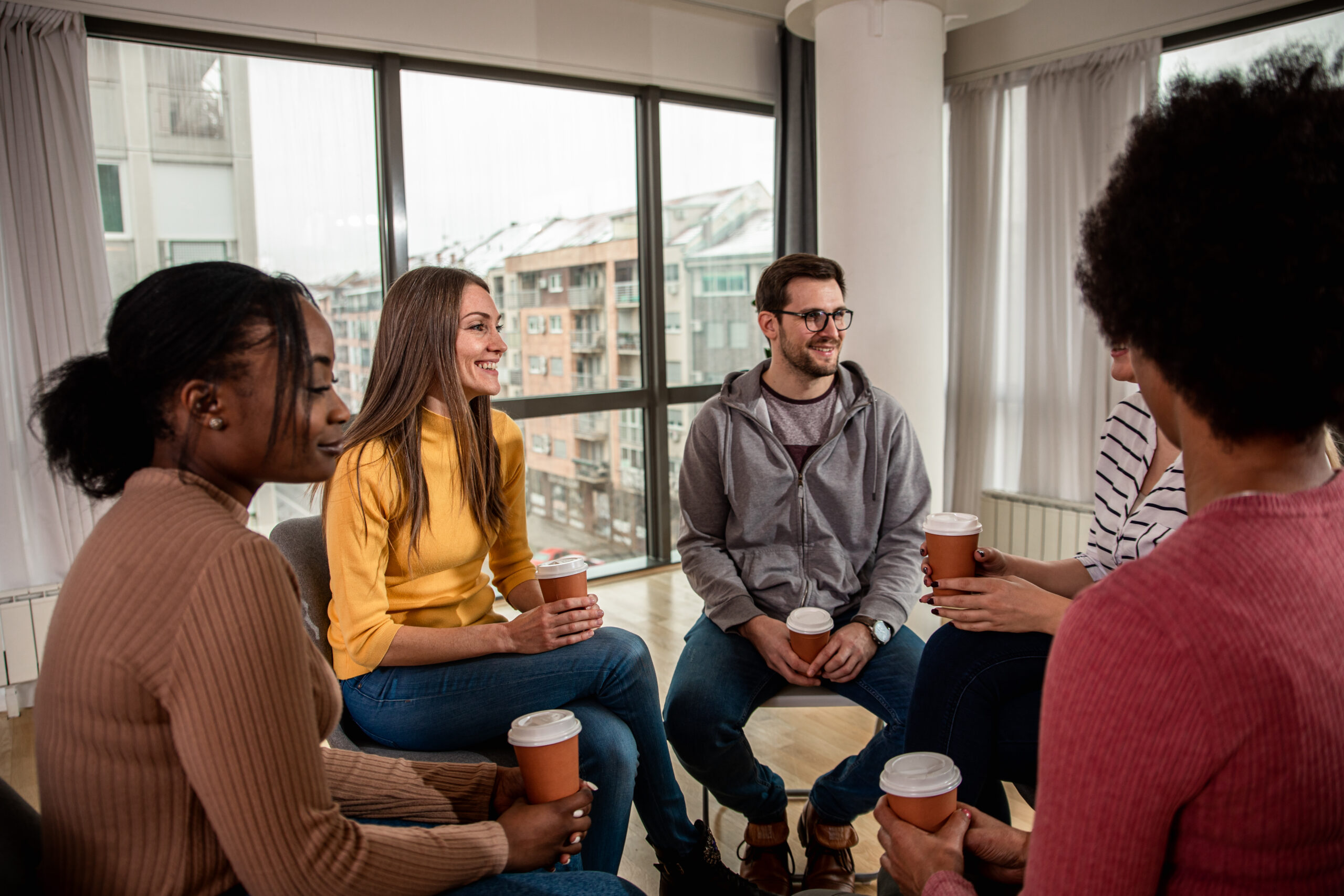 Diverse group of people sitting in circle in group therapy sessi