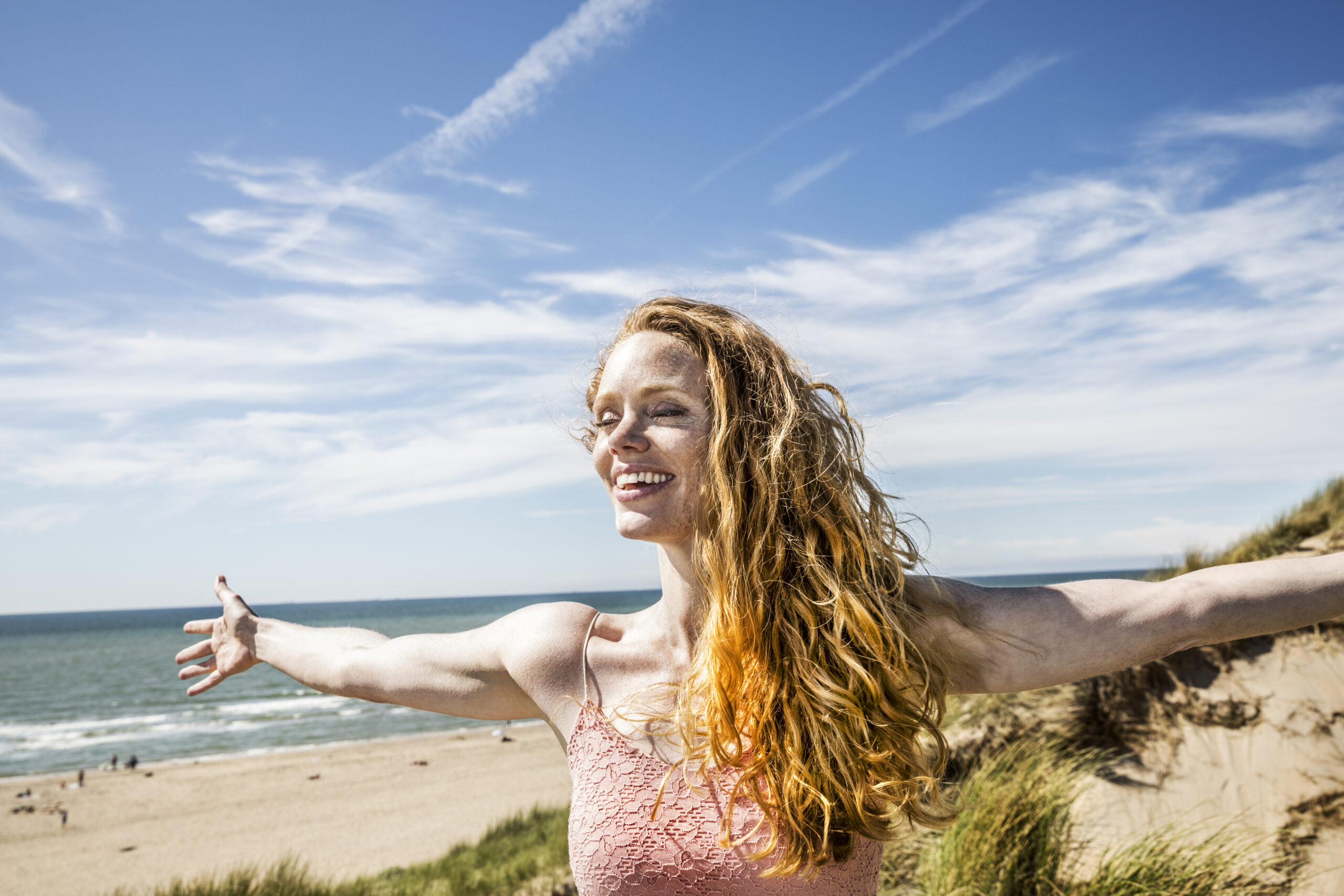 Netherlands, Zandvoort, happy woman standing in dunes with outstretched arms