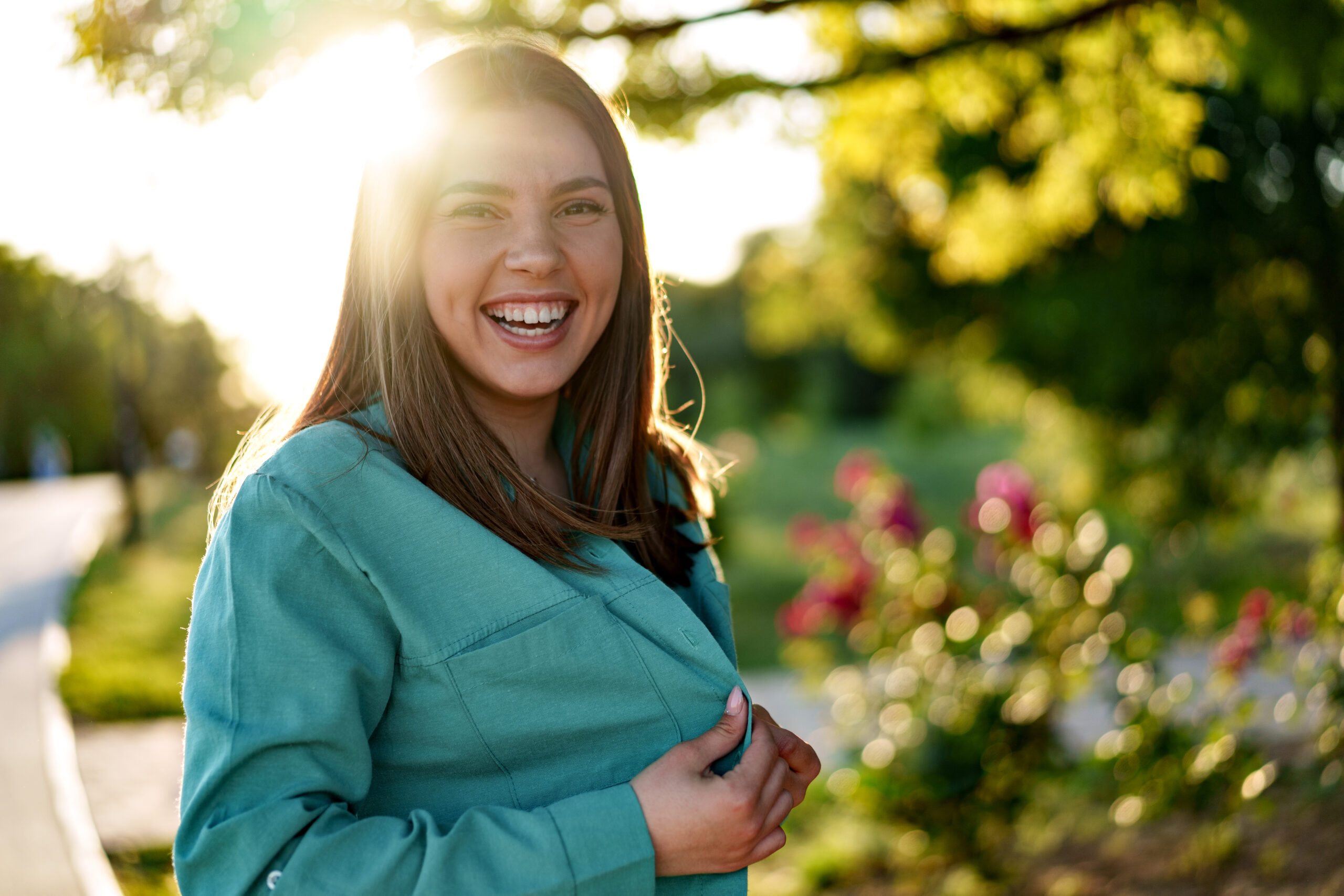 Portrait of young woman in green shirt smiling in a park